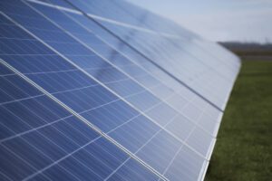 Painéis solares alinhados em um campo verde, captando energia solar em um dia claro.