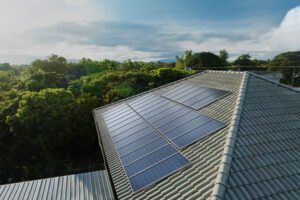 Painéis solares instalados no telhado de uma casa cercada por árvores.